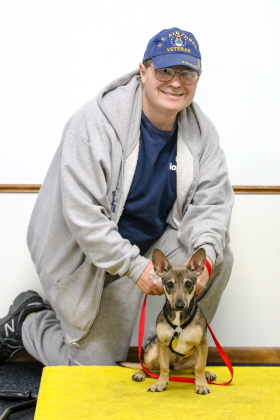 Small dog sits with owner for obedience class photo